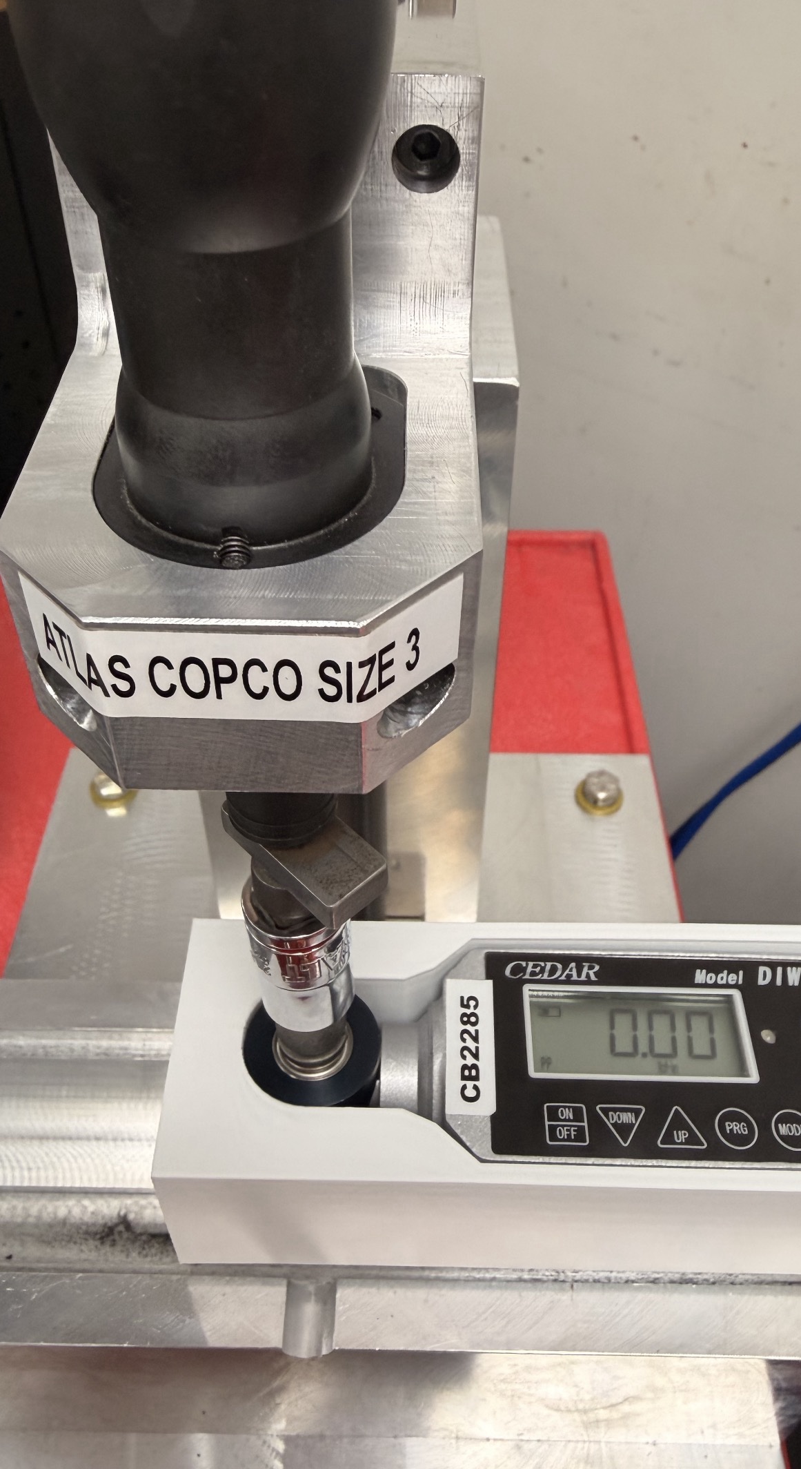Digital torque wrench in a white 3D-printed holder beneath the Atlas Copco screwdriver