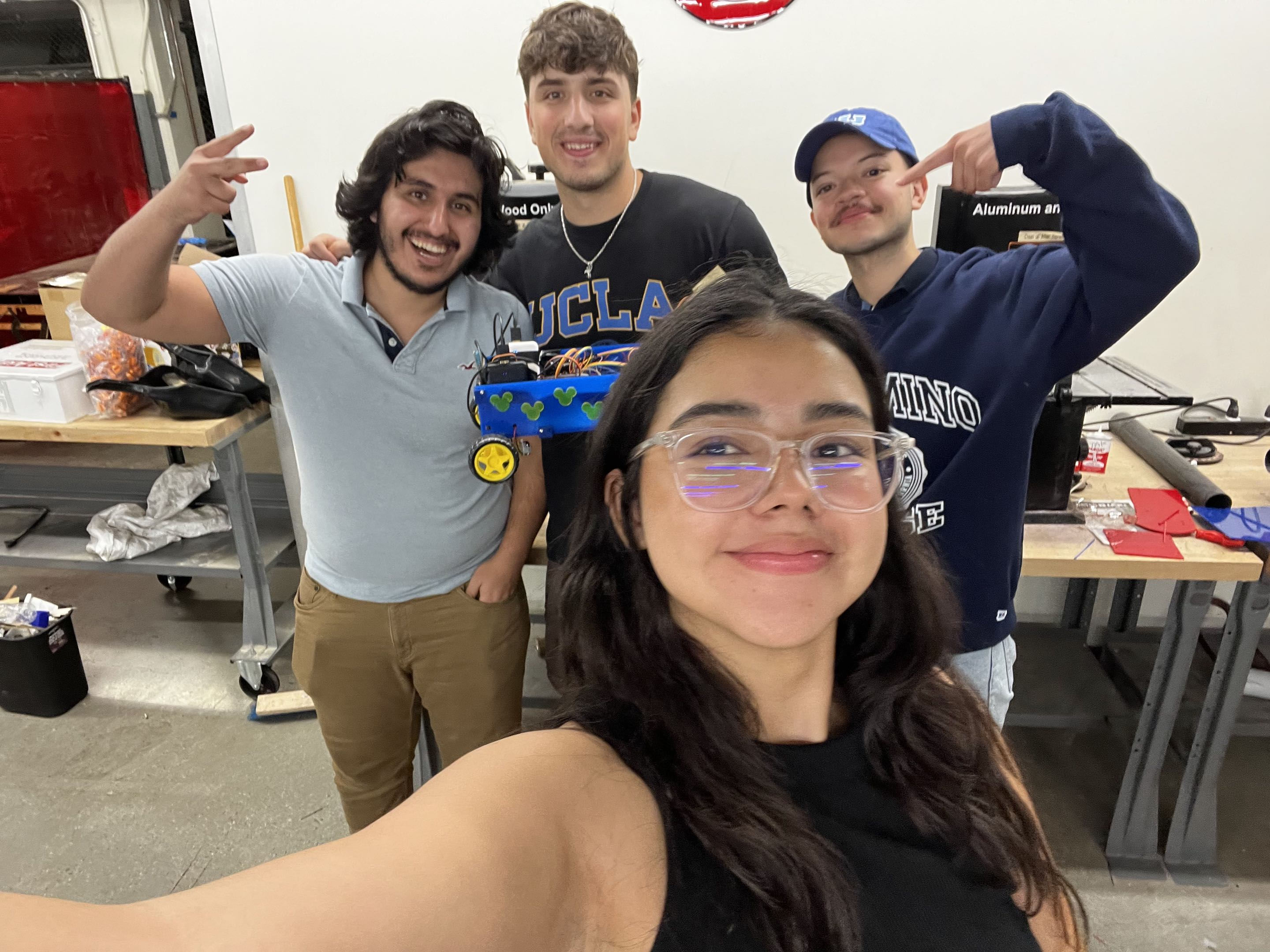 Rover project team and mentor posing together with the completed rover in the workshop